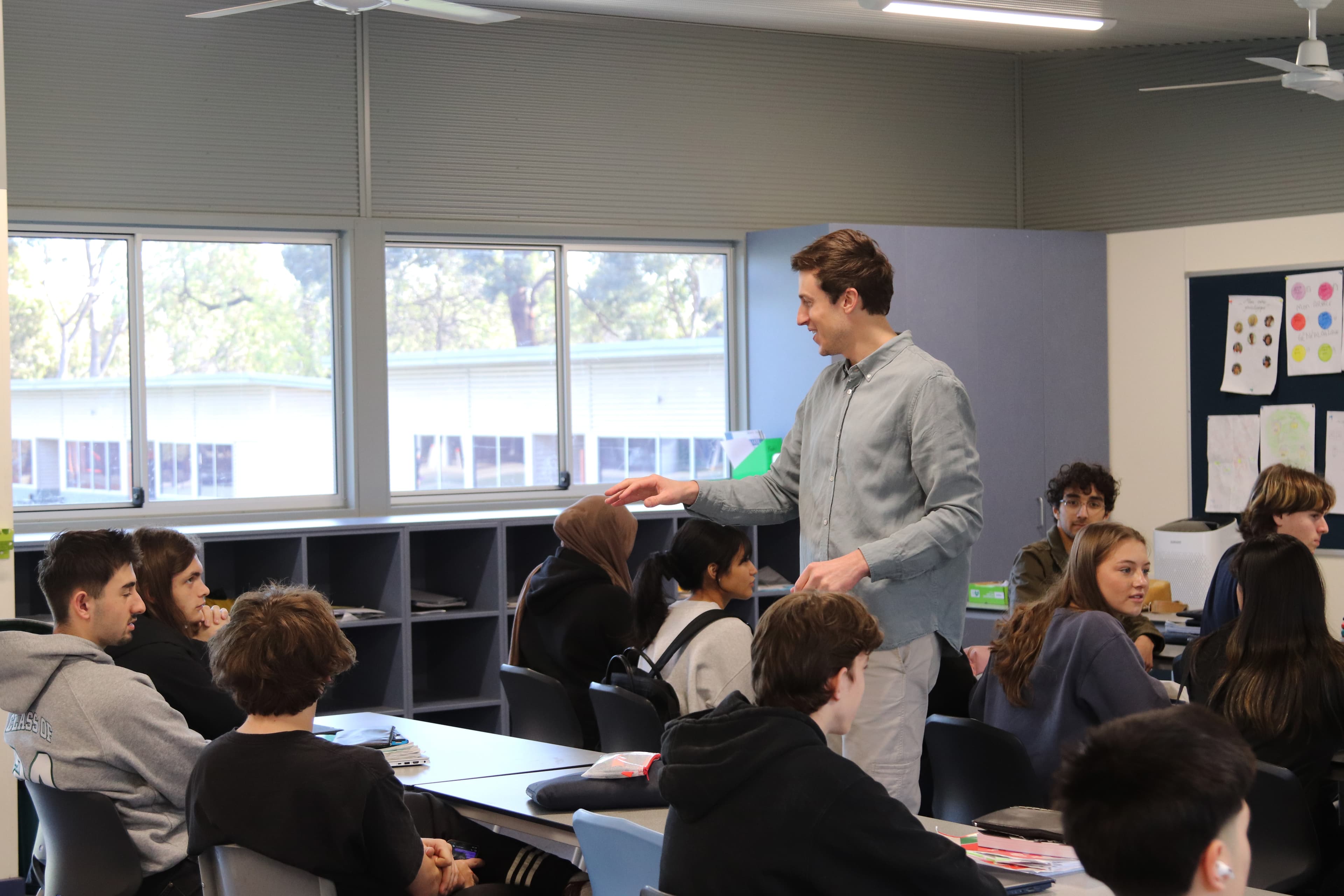 Chris standing among students, laughing and holding papers